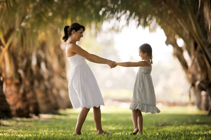 Mother and daughter holding hands in park