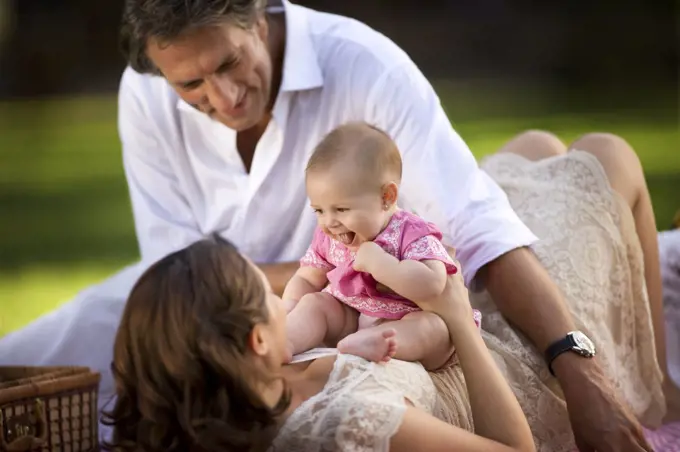 Young family lie on the grass having a picnic.