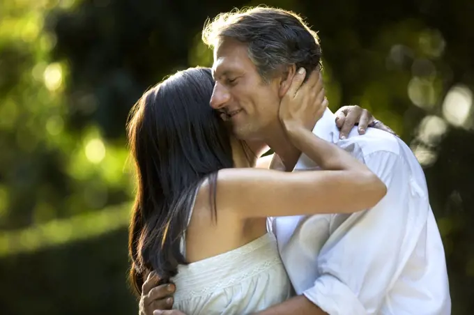 Husband and wife stand in embrace.