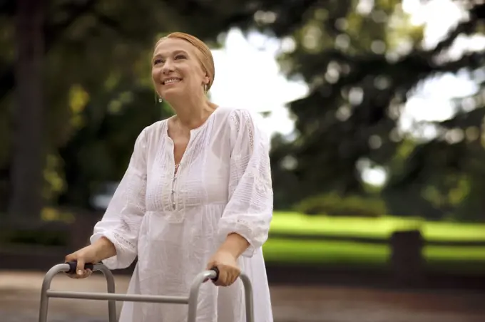 Elderly woman using a walker outdoors.