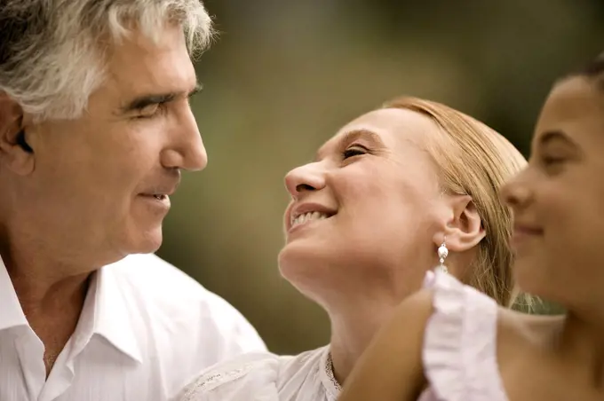 Elderly couple sit looking into each others eyes.