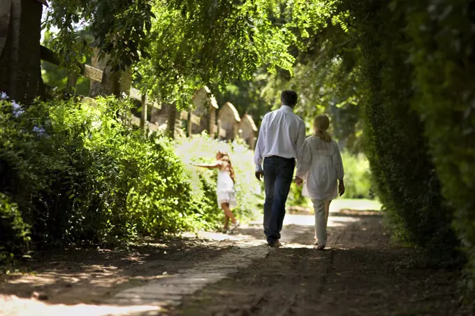 Elderly couple and their granddaughter walk down a quiet country road.