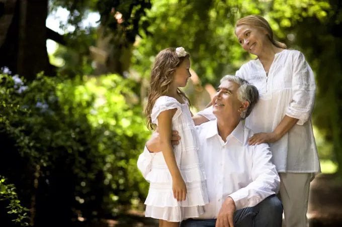 Grandparents stand with their granddaughter on a quiet country road.