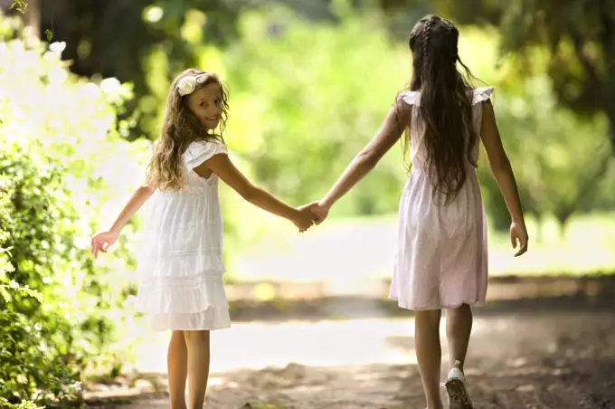 Two young girls walk down a quiet country road. 