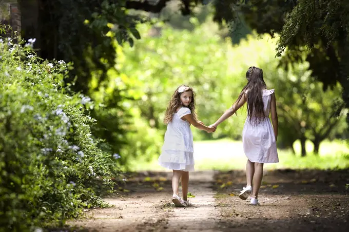 Two young girls walk down a quiet country road. 