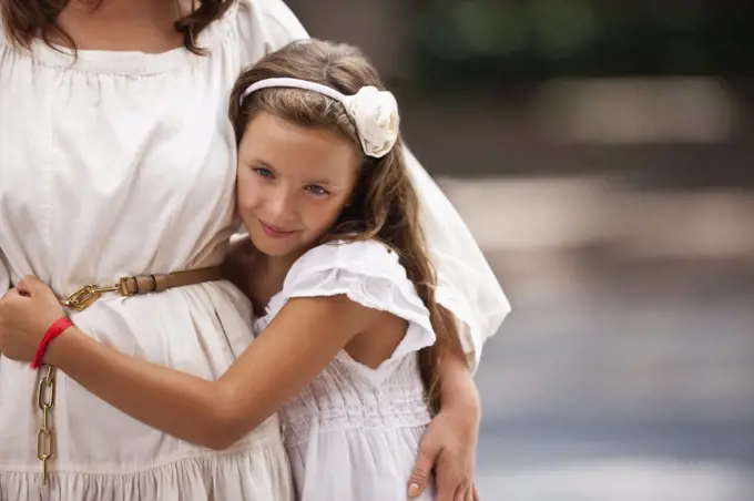 Portrait of a young girl standing beside her mother. 