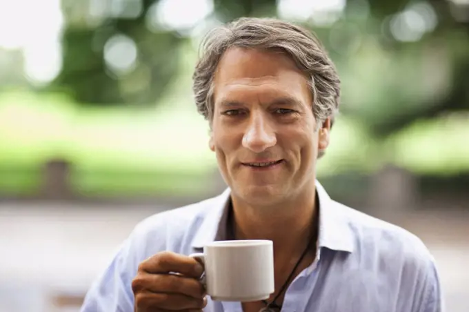 Portrait of a mature man outdoors drinking a cup of coffee.