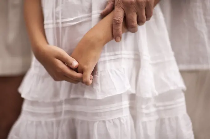 Grandmother holds the arm of her granddaughter.