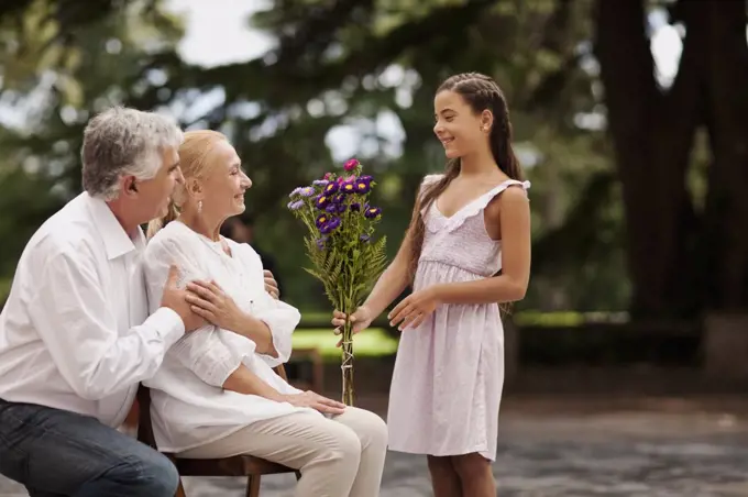 Young girl presents her grandmother with a bouquet of flowers.