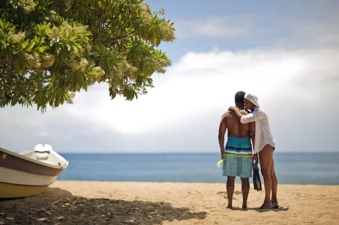 Mature woman hugging her husband at the beach.