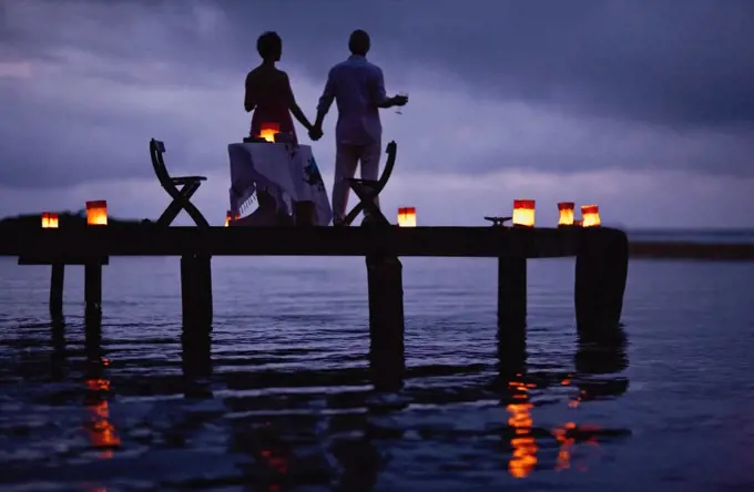 Mature couple enjoying their date on the pier at twilight.