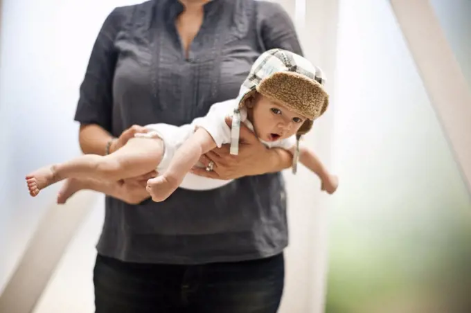 Baby held in mid air by its mother.