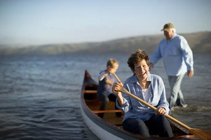 Portrait of a happy mature couple canoeing with their young grandson.