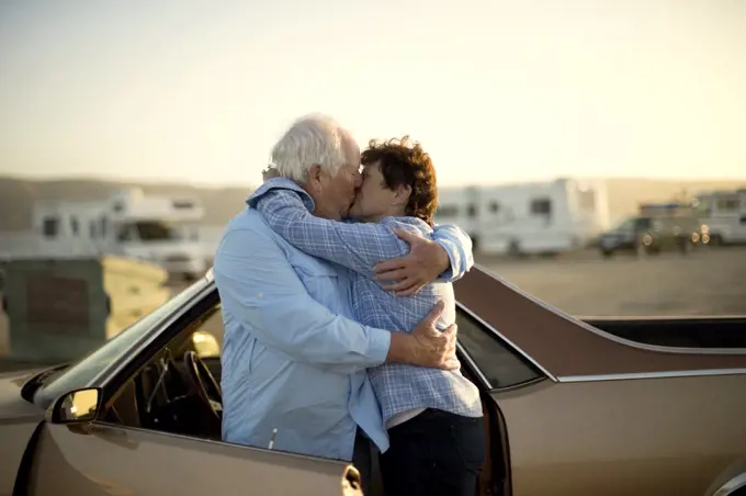 Mature couple embracing by a car.