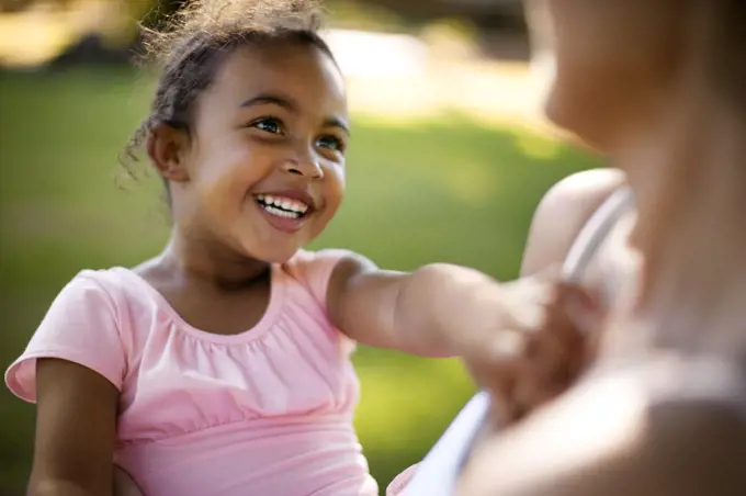 Young girl looking up at her mother and smiling.