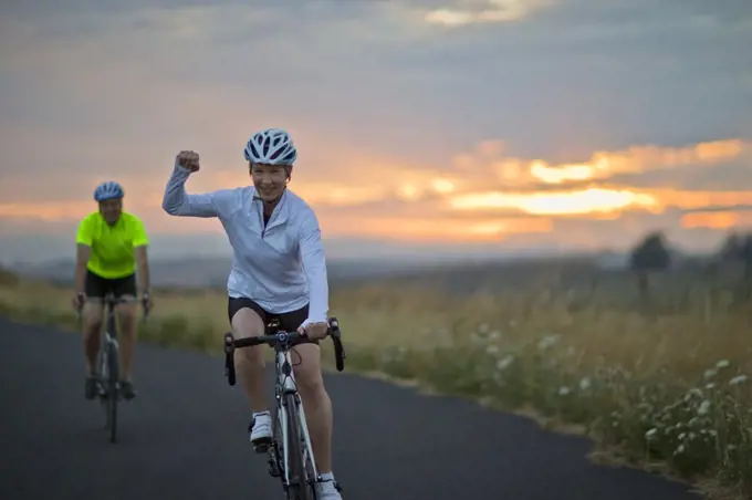 Portrait of a happy mature couple cycling along a country road.