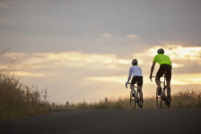 Mature couple cycling along a country road.