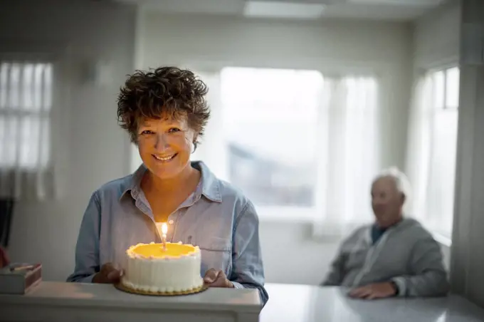 Portrait of a smiling mature woman holding a birthday cake.