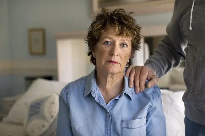 Portrait of a depressed mature woman sitting sadly on her bed.