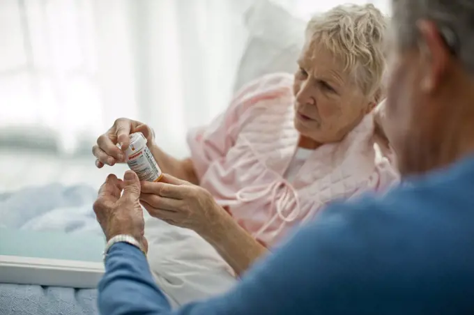 Senior man helping his puzzled wife read the instructions on her medicine bottle.