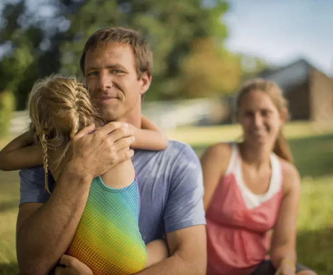 Portrait of a middle-aged father gently hugging his young daughter.