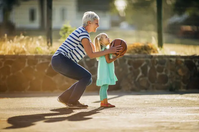 Grandmother and granddaughter playing basketball together.