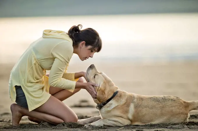 Mid adult woman playing with her dog at the beach.