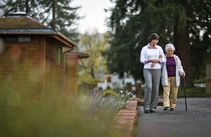 Elderly woman walking arm in arm with her doctor.