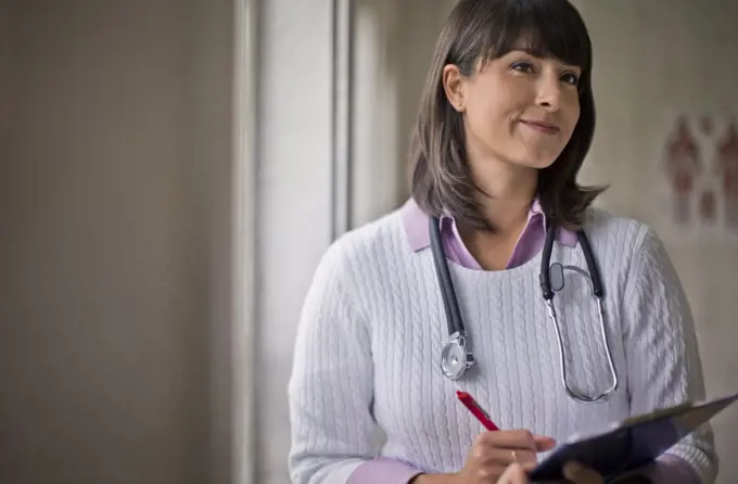 Portrait of a young female doctor holding a clipboard in her office.