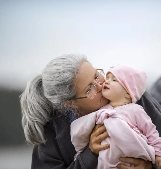 Grandmother holding her baby granddaughter on the beach.