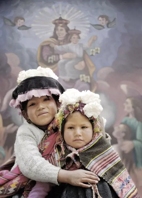 A young girl embraces a chubby looking girl and smiles.