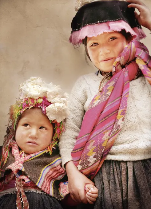 A young girl smiles holding her sisters hand.