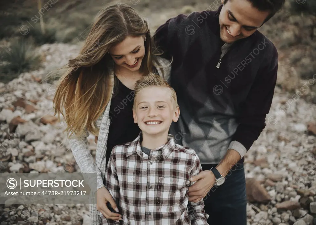 Three people, two adults and a child, a family portrait of parents and a boy, outdoors. 