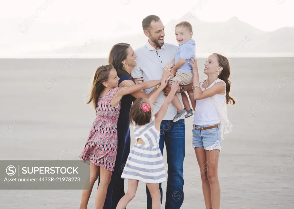 A large family on the beach, two adults and four children. 