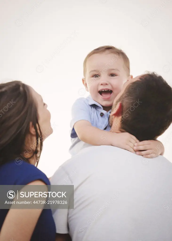 A family, a mother and father and a young boy being held by his father.