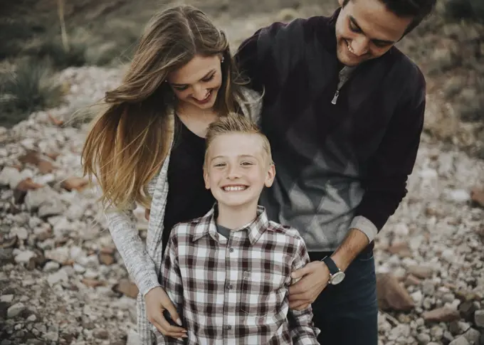 Three people, two adults and a child, a family portrait of parents and a boy, outdoors. 