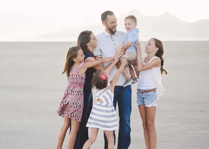 A large family on the beach, two adults and four children. 