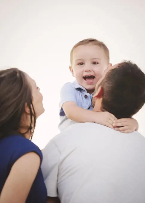 A family, a mother and father and a young boy being held by his father.