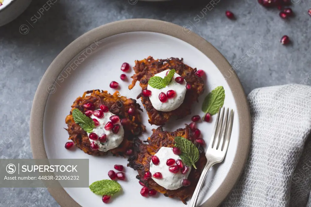 Harissa sweet potato latkes with spiced yogurt, mint and pomegranate, gluten-free.