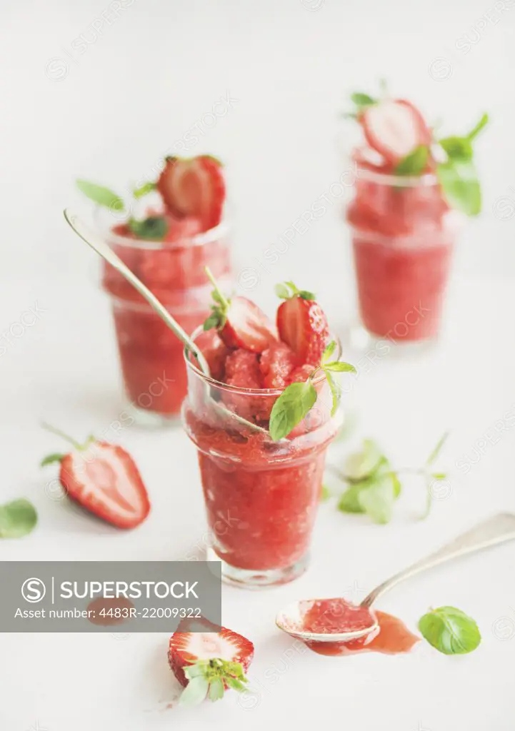 Healthy low calorie summer treat. Strawberry and champaigne granita, slushie or shaved ice dessert in glasses with mint, white background. Clean eating, vegan, dieting food concept