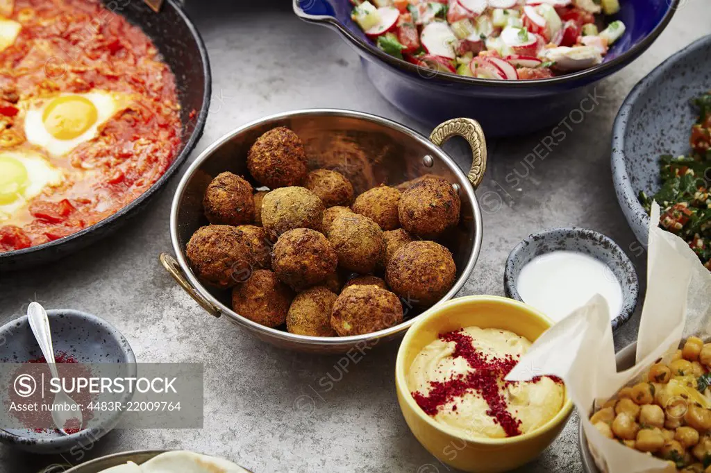 Side view of traditional jewish and middle eastern food: falafel, fattoush, tabouli, shakshuka, balila, hummus and spicy beetroot dip. Israeli cuisine concept