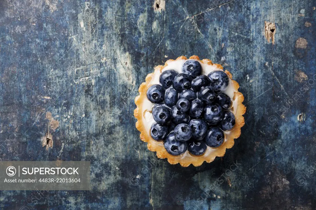 Blueberry tart on blue wooden background