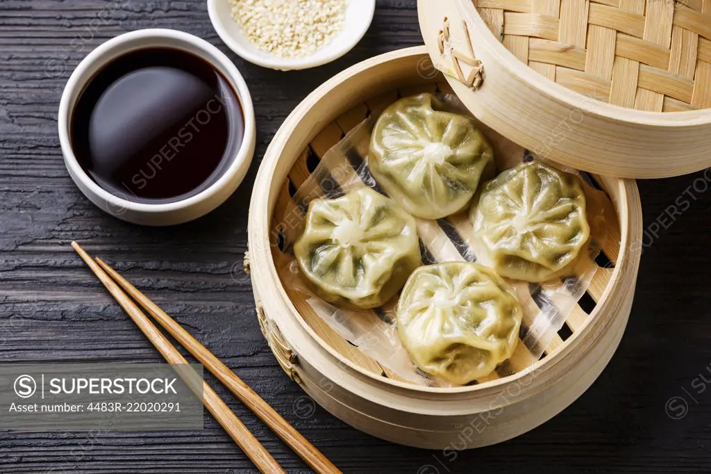 Steamed dumplings Dim Sum in bamboo steamer on black burned wooden background