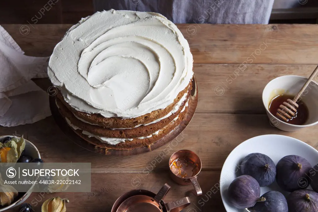 Honey layer cake being decorated on wooden table