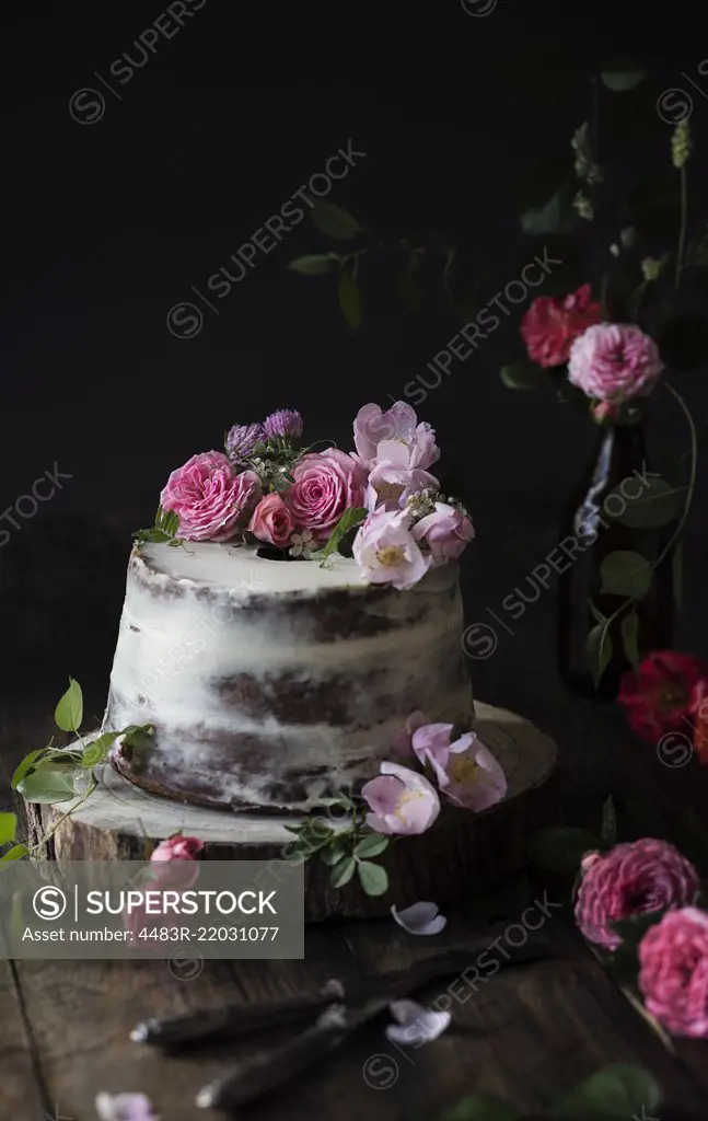 Naked cake decorated with roses on wooden table