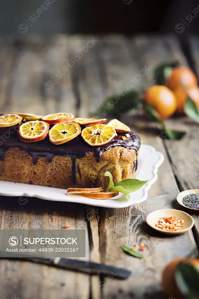 Tangerine loaf cake with chocolate glaze on rustic wooden table