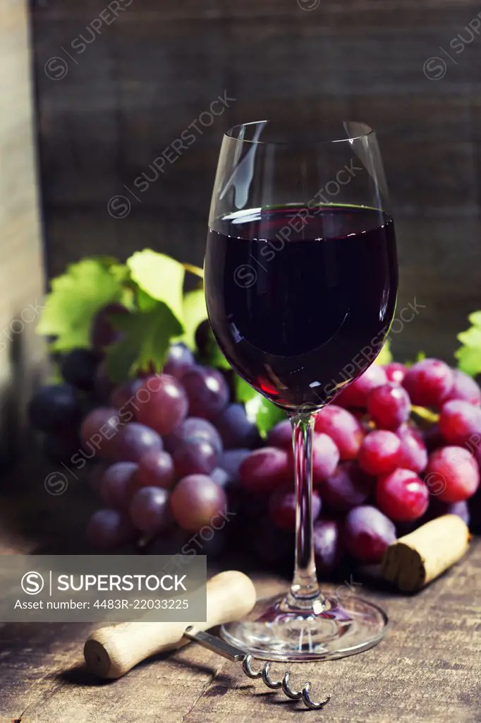 Red wine and red grapes on wooden background.