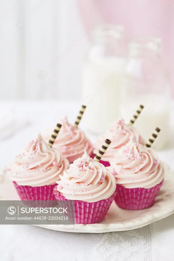 Pink cupcakes decorated with stripey chocolate straws