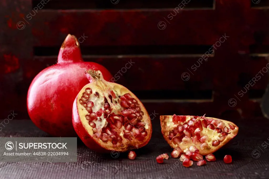 Pomegranate Seeds , some peeled and whole on a dark background