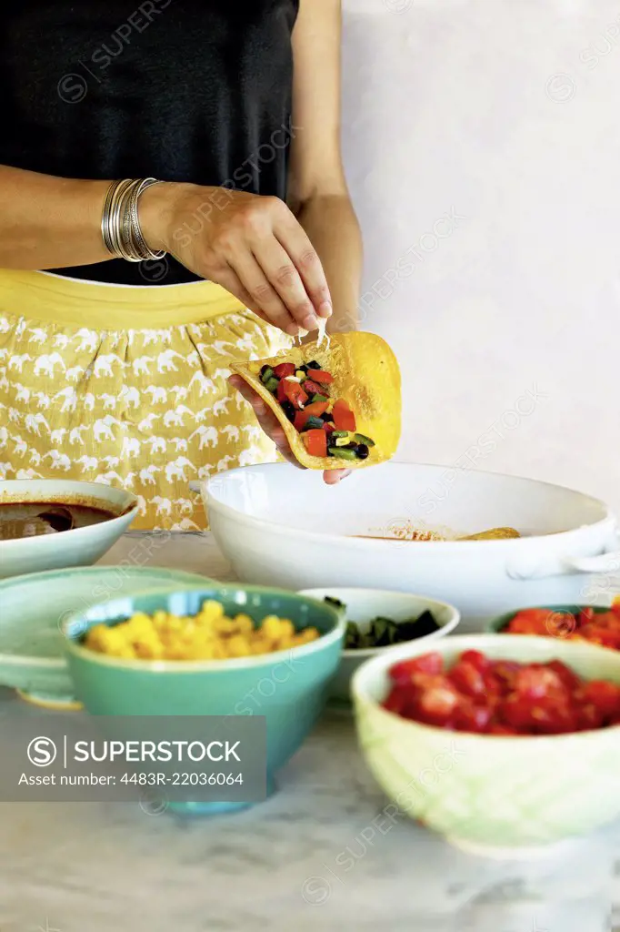 A woman making Black Bean Vegetable Enchiladas with home made enchilada sauce.